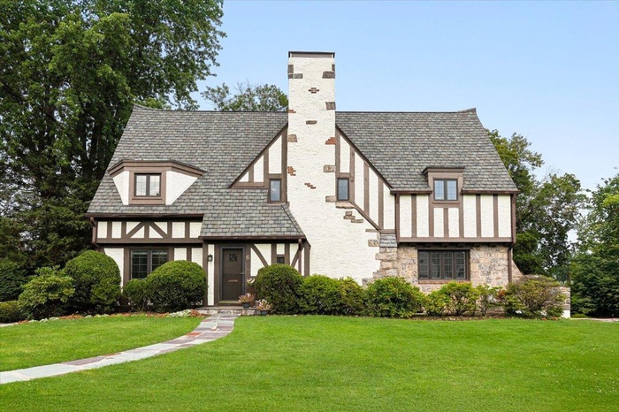 View of front of home featuring stone siding, a front yard, stucco siding, and a chimney