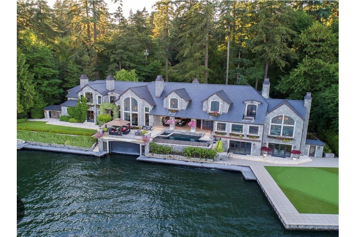 Rear view of house with a chimney, a patio area, a water view, and a forest view
