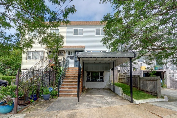 View of front of property with stairway, a carport, and concrete driveway