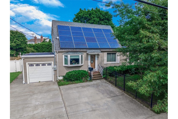 View of front of property with roof mounted solar panels, concrete driveway, a garage, and a shingled roof