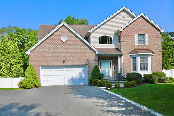 Traditional home featuring asphalt driveway, a garage, brick siding, and a shingled roof