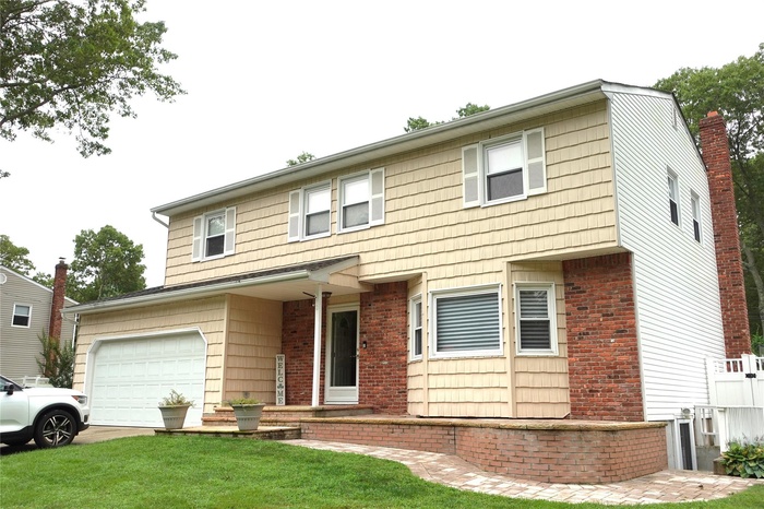 View of front facade with a front yard, a garage, concrete driveway, and brick siding