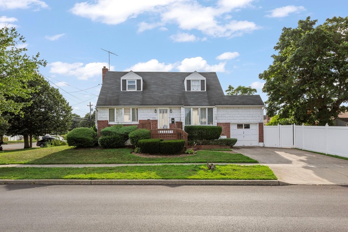 Cape cod-style house featuring driveway and brick siding