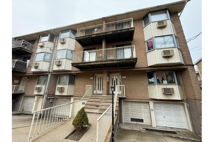 View of property with an attached garage, concrete driveway, and a wall unit AC