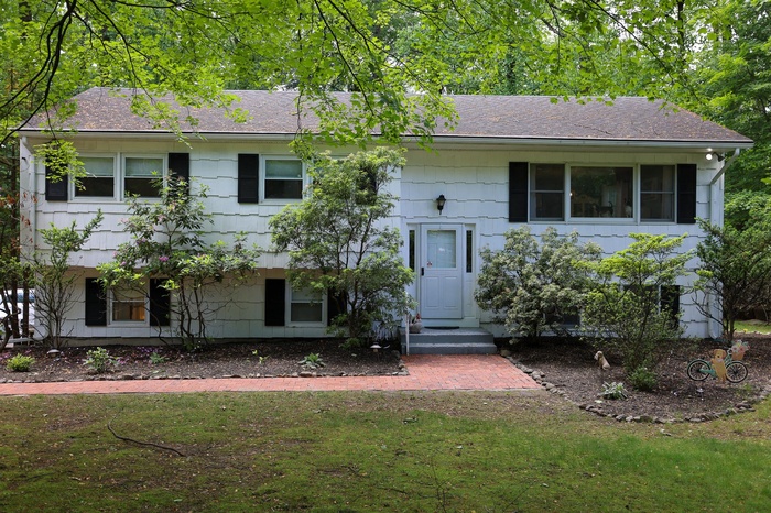 Raised ranch featuring a front yard and roof with shingles