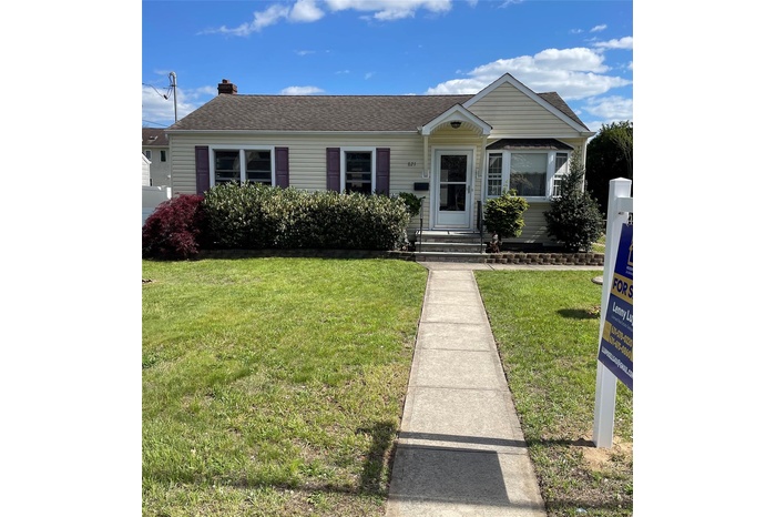 View of front facade with a front yard, a chimney, entry steps, and roof with shingles