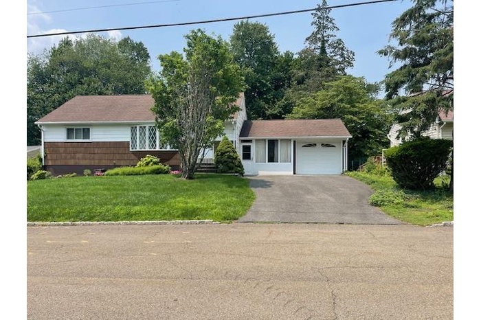 View of front facade featuring asphalt driveway, a garage, and a front yard