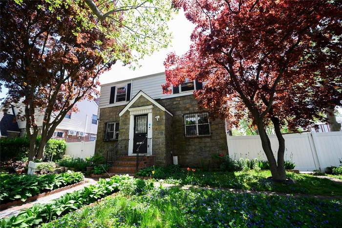 View of front of property featuring stone siding and fence