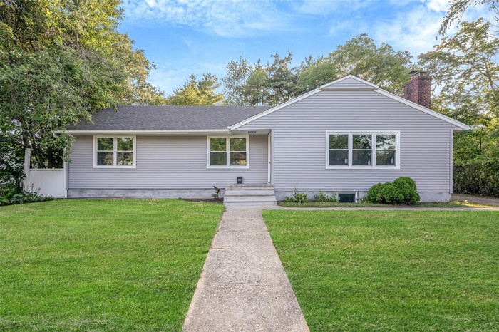 Ranch-style house featuring a front yard, a chimney, and a shingled roof