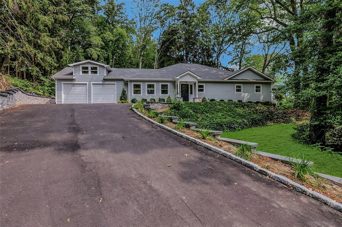 Ranch-style home featuring driveway, an attached garage, a front lawn, and roof with shingles