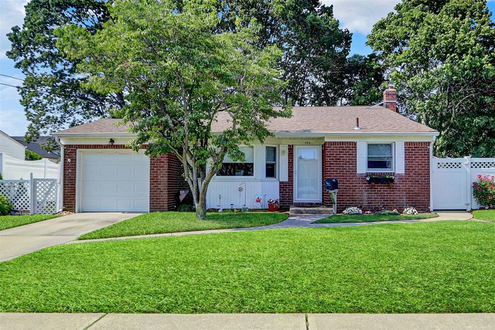 View of front of property featuring an attached garage, roof with shingles, brick siding, concrete driveway, and a chimney