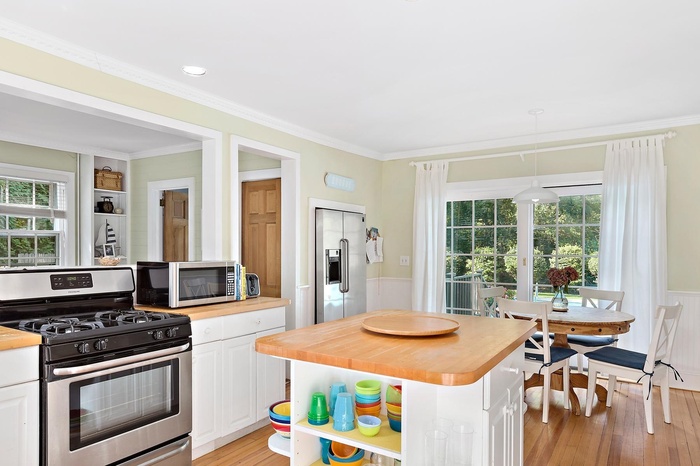 Kitchen featuring butcher block counters, stainless steel appliances, crown molding, white cabinetry, and open shelves