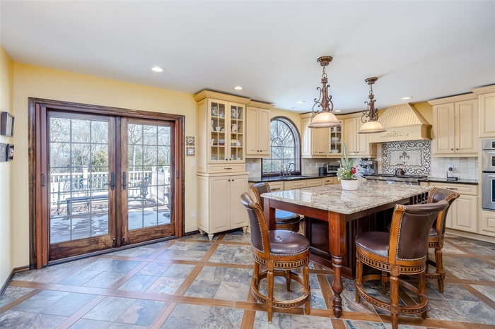 Kitchen featuring sink, premium range hood, pendant lighting, a center island, and decorative backsplash