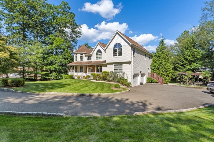 View of front of home with a garage, driveway, a front yard, and a porch