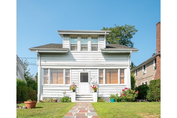 View of front of house with entry steps, a front lawn, and a shingled roof