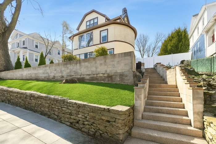 View of side of home featuring a lawn, stairs, and fence