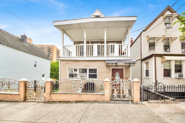 View of front of property with a balcony, a gate, and a fenced front yard