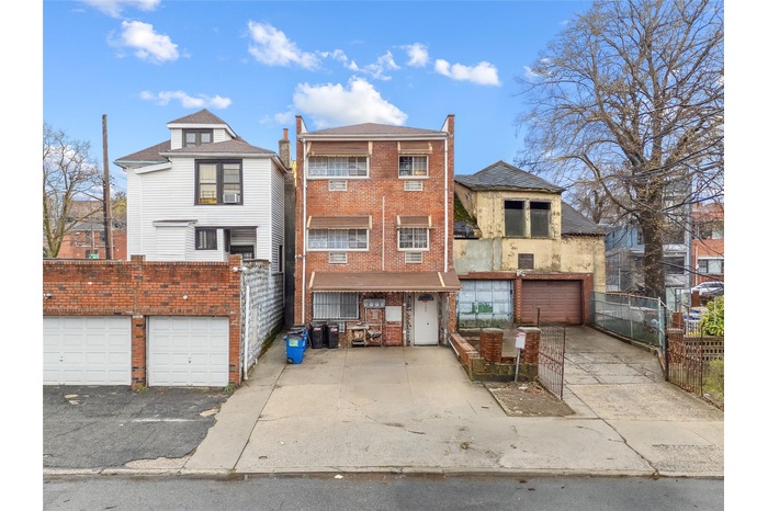 View of front of home featuring brick siding, fence, a garage, and aphalt driveway