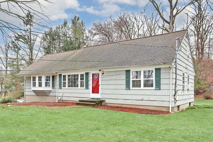 View of front of house featuring a shingled roof and a front lawn