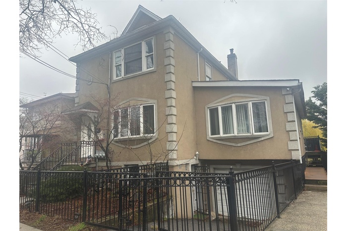 View of side of home featuring stucco siding, a fenced front yard, and a chimney
