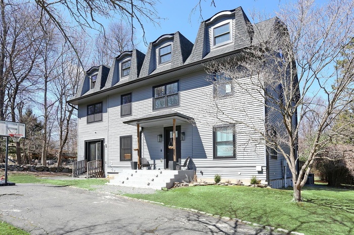 View of front of house featuring a shingled roof and a front yard