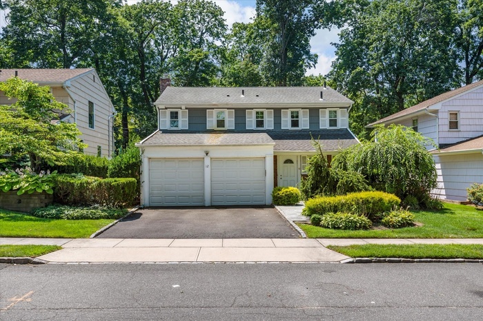 Traditional-style home featuring asphalt driveway, a chimney, and roof with shingles