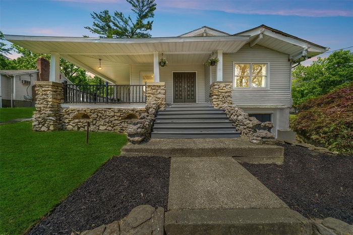 View of front facade featuring a porch, a front yard, french doors, and stairs