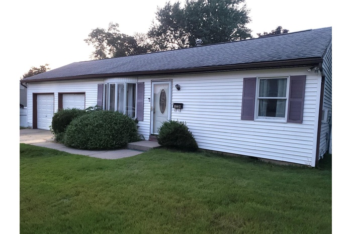 Ranch-style home featuring a garage, roof with shingles, a front yard, and concrete driveway