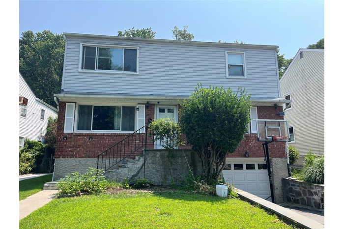 View of front of home with a garage, a front lawn, and brick siding