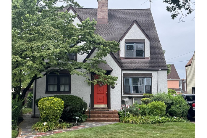 English style home with a shingled roof, a chimney, and stucco siding