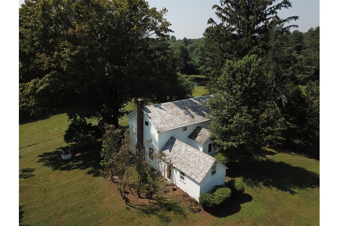 Aerial view of property and surrounding area with a heavily wooded area