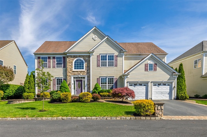 View of front of house featuring asphalt driveway, a front lawn, a garage, and stone siding