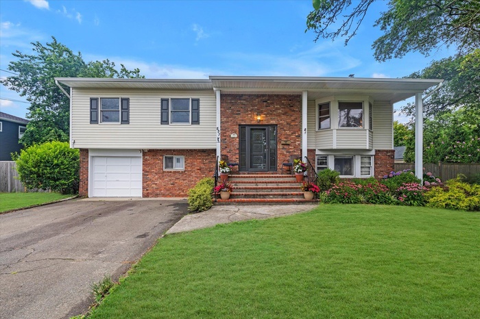Split foyer home with brick siding, driveway, and a garage