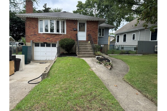 View of front of house with a garage, brick siding, a chimney, and concrete driveway