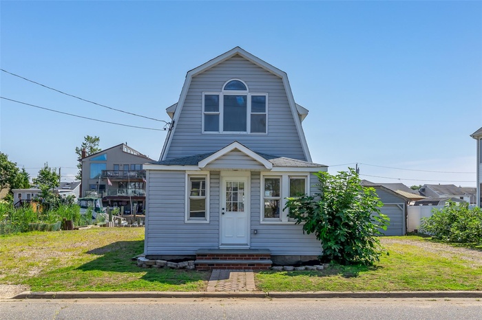 Colonial inspired home with a gambrel roof and a front yard