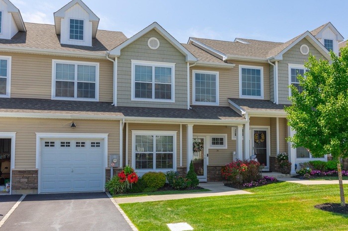 Craftsman inspired home featuring roof with shingles, a front yard, driveway, and stone siding