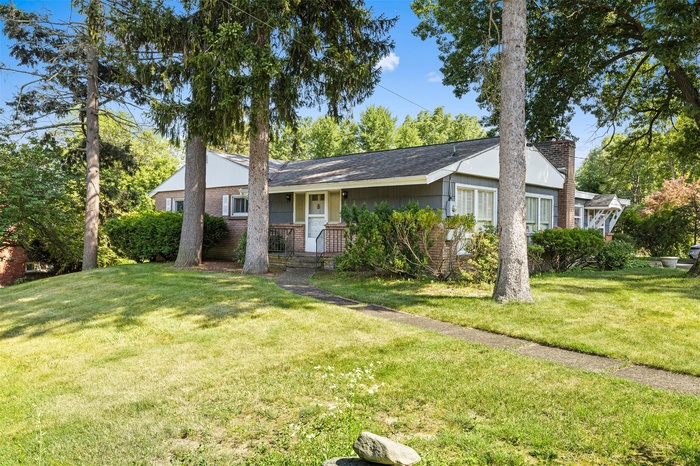 Ranch-style house featuring brick siding, a front lawn, and a chimney