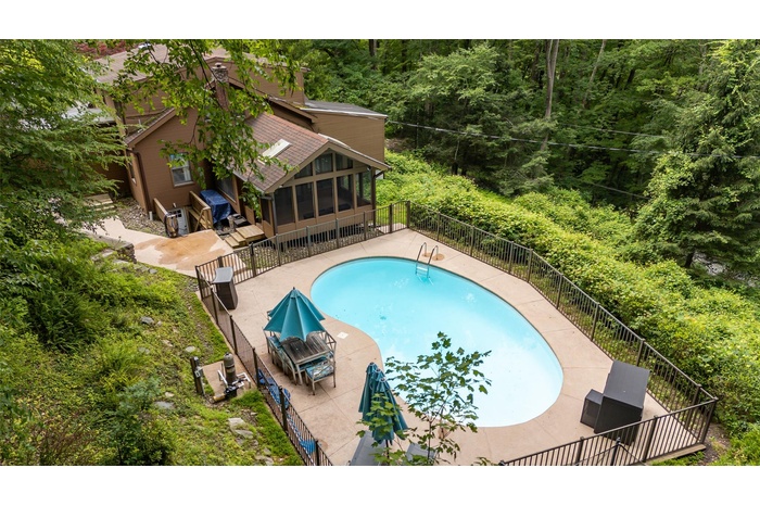 View of pool featuring a sunroom, a patio, and a forest view