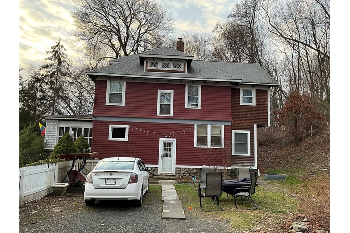 American foursquare style home with a chimney, a shingled roof, entry steps, and stone siding