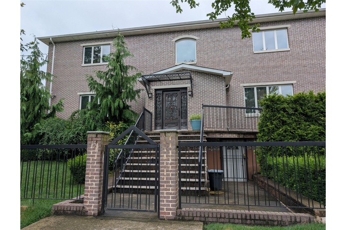 View of front of property featuring a fenced front yard, brick siding, and a gate