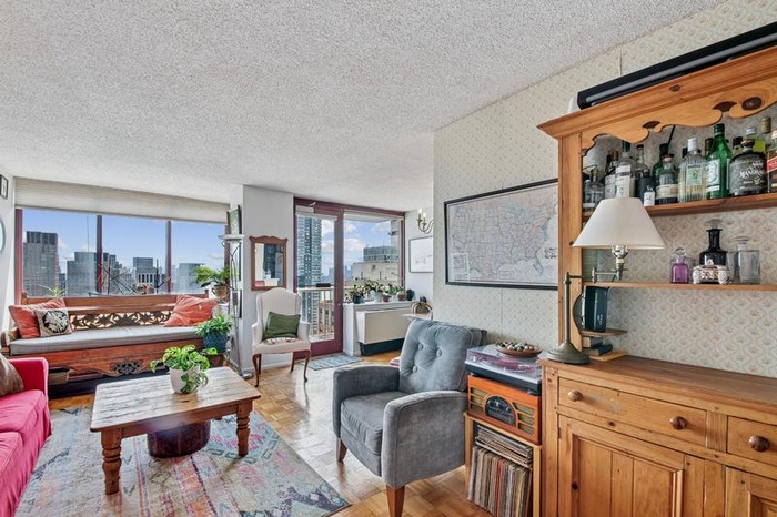 Living area with a textured ceiling, wallpapered walls, and a view of city