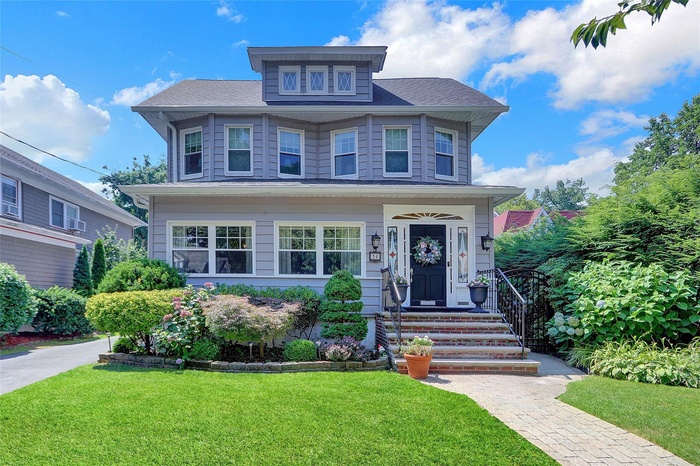 American foursquare style home featuring a front lawn and roof with shingles