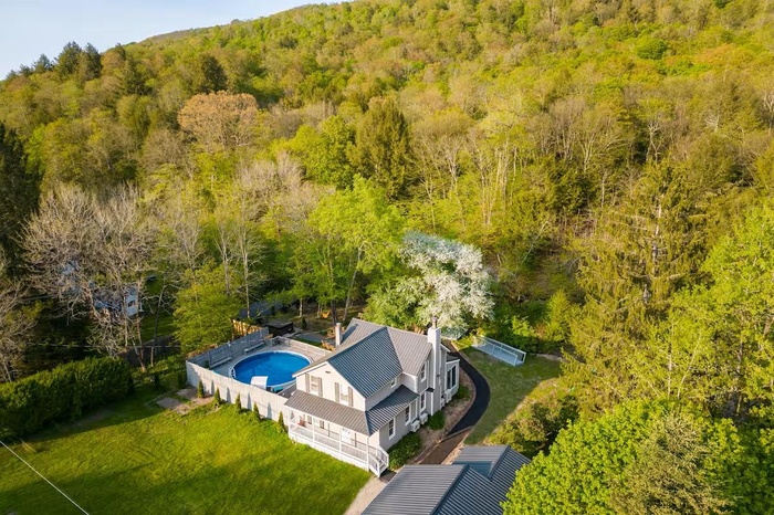 View from above of property featuring a heavily wooded area and a pool area