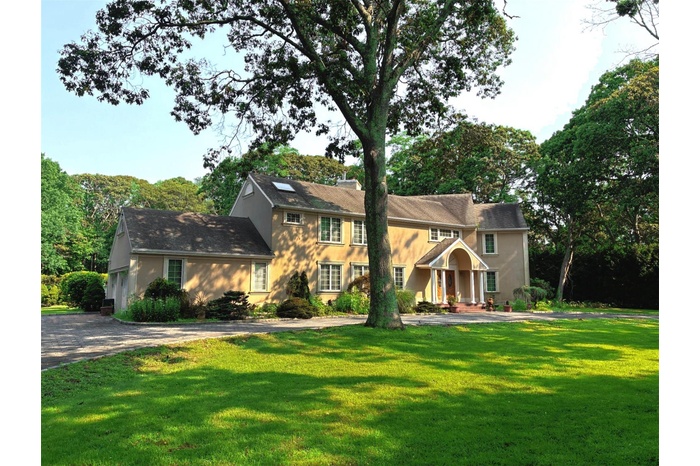 Colonial inspired home with stucco siding, a front yard, driveway, and a garage