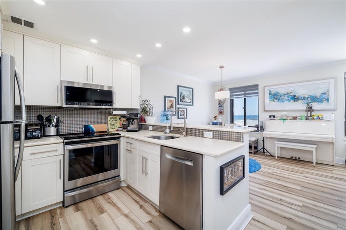 Kitchen with stainless steel appliances, decorative backsplash, crown molding, and creamy white cabinets