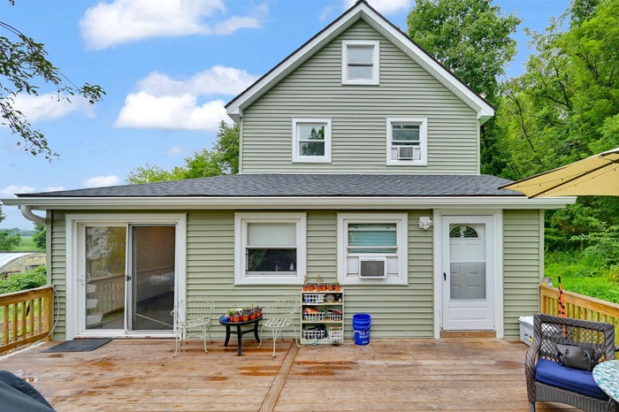 Rear view of property featuring a deck and a shingled roof
