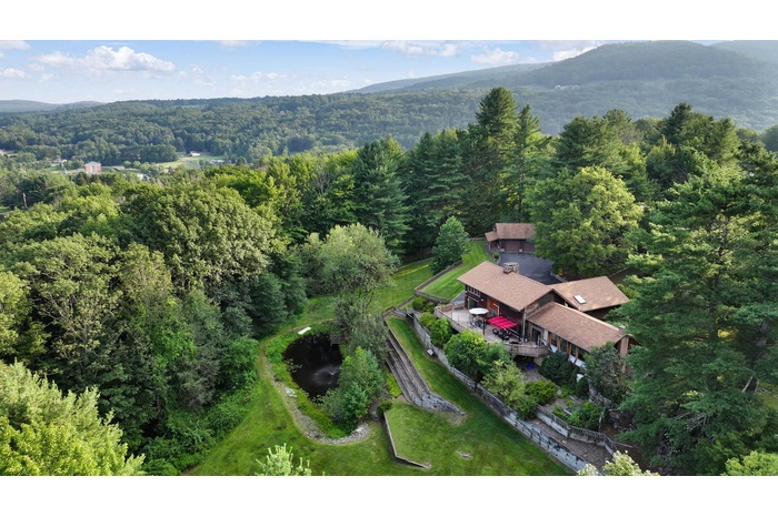 Aerial view of property's location featuring a forest and a mountain backdrop