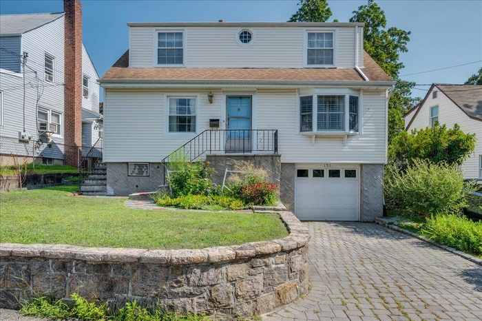 View of front of house featuring an attached garage, a front lawn and driveway