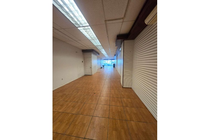 Corridor featuring a wall unit AC, a paneled ceiling, and wood walls