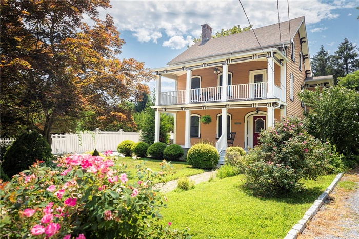 View of front of property with a balcony, a chimney, and covered porch